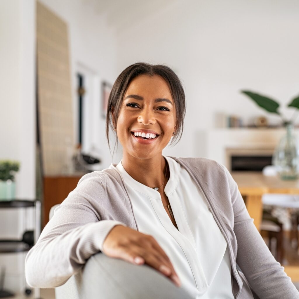 Smiling young woman sitting comfortably on a couch at home.