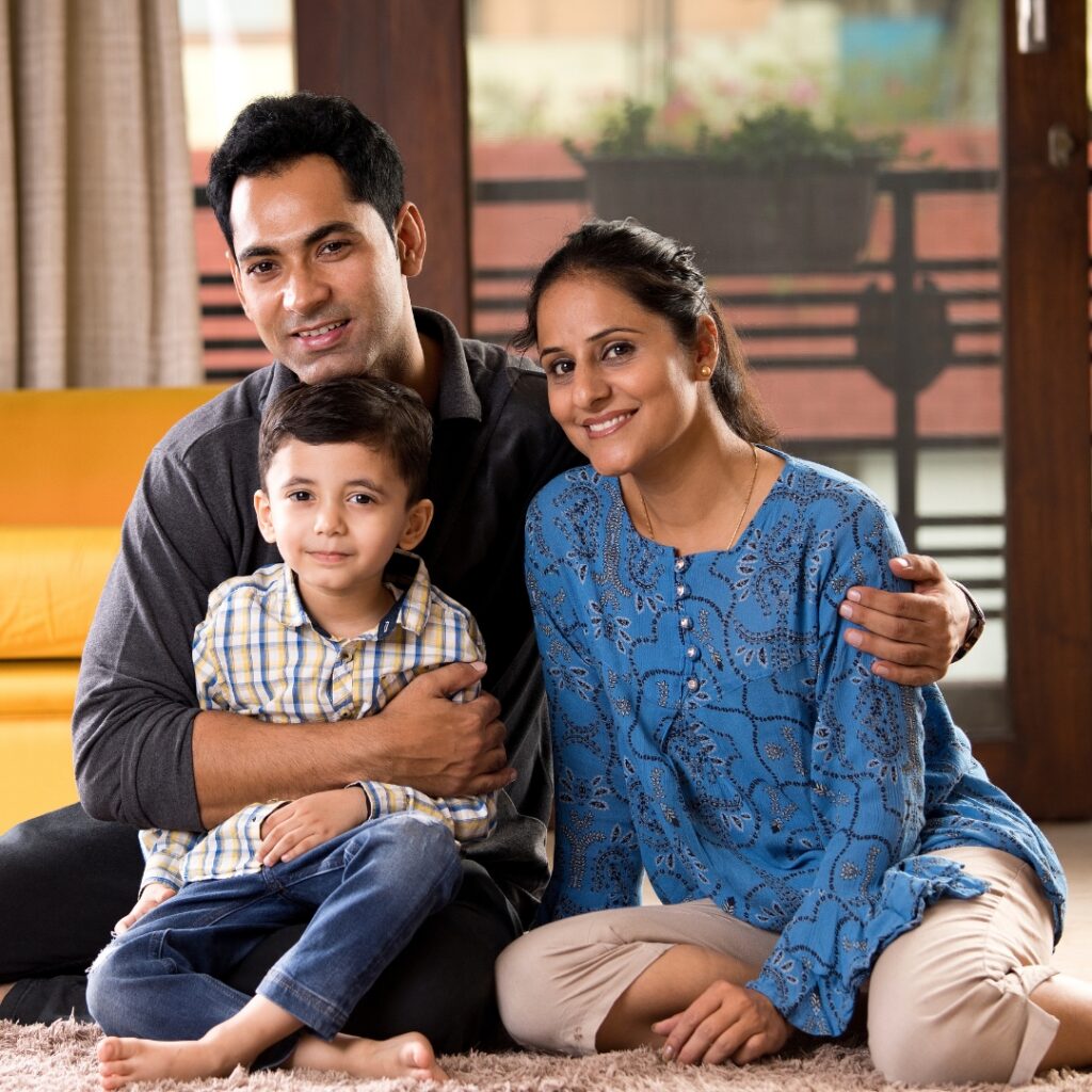 Happy family of three sitting together indoors on the floor.