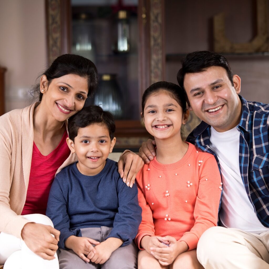 Happy family of four sitting together on a couch at home.