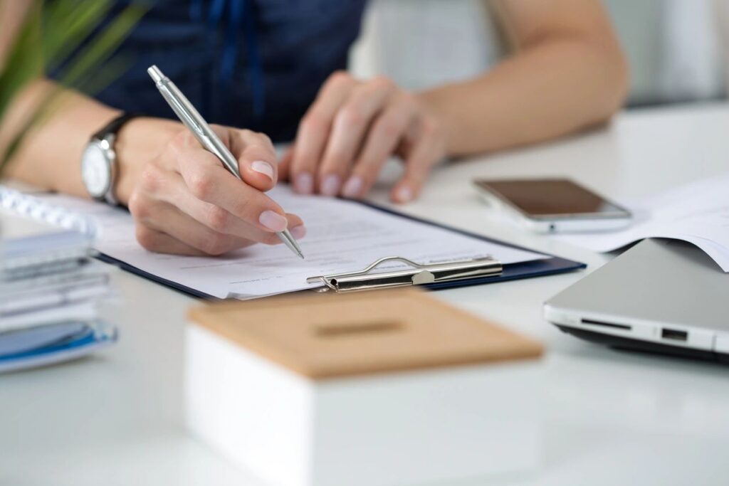 A photo of a woman's hand signing a paper.