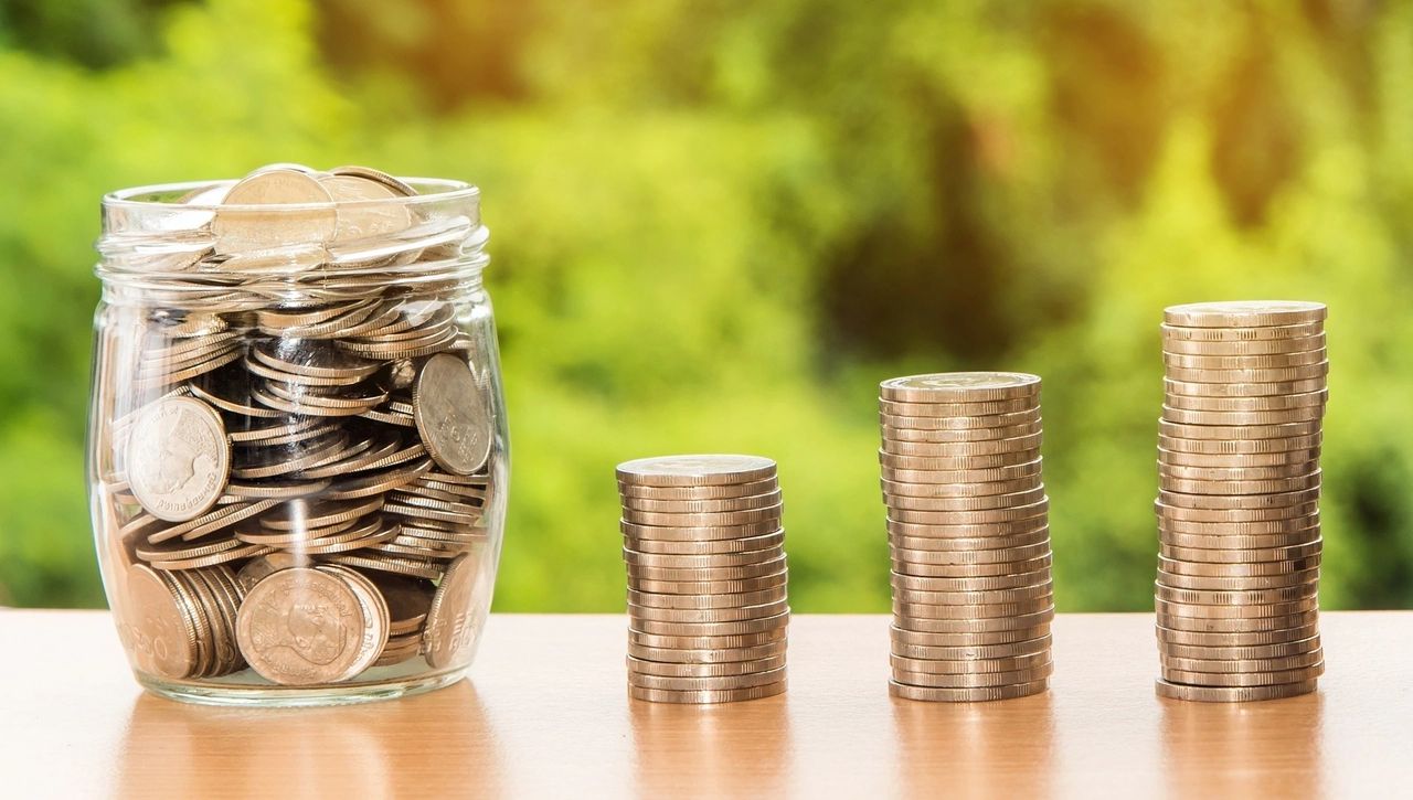 A photo of coins in a jar and a pile of coins stacked together. 